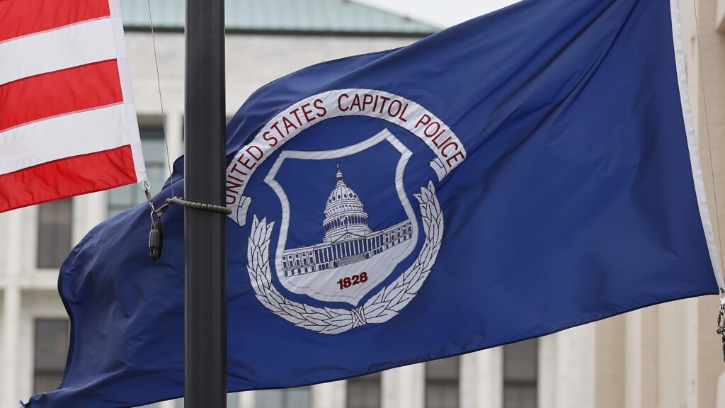 The U.S. and U.S. Capitol Police flags were flown at half-staff after the death of officer Brian Sicknick. On Sunday, the FBI arrested two men who are accused of spraying chemicals on Sicknick and others. CREDIT: Chip Somodevilla/Getty Images