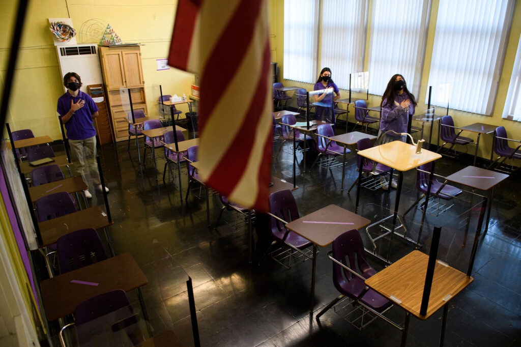 Students stand for the Pledge of Allegiance as they return to in-person learning at St. Anthony Catholic High School in California on March 24. Masks and physical distancing are proving to have some major public health benefits, keeping people from getting all kinds of illnesses, not just COVID-19. But it's unclear whether the strict protocols would be worth the drawbacks in the long run. CREDIT: Patrick T. Fallon/AFP via Getty Images