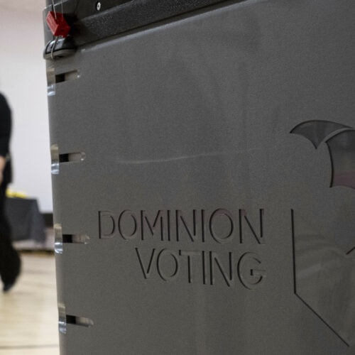 A worker passes a Dominion Voting Systems ballot scanner during Georgia's runoff Senate elections in January in Gwinnett County outside Atlanta. Former President Donald Trump and his allies spread falsehoods about the company's role in the 2020 election, leading to a slew of defamation lawsuits. Ben Gray/AP
