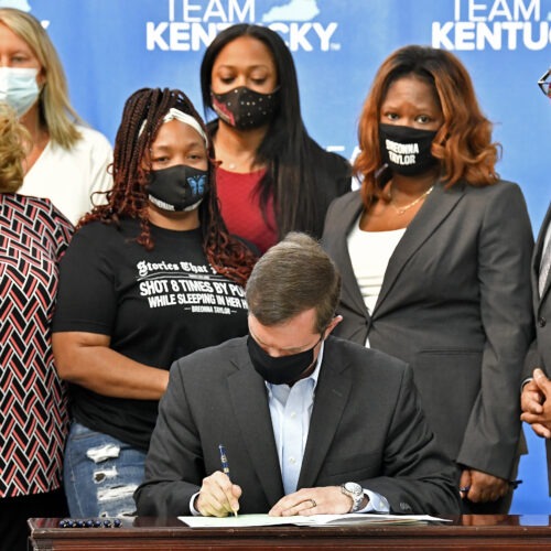 Kentucky Gov. Andy Beshear signs a bill on Friday limiting the use of no-knock warrants statewide. The governor was surrounded by members of Breonna Taylor's family including her mother, Tamika Palmer (standing behind Beshear at left). CREDIT: Timothy D. Easley/AP