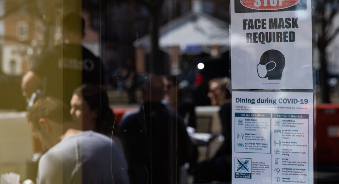 A sign requiring face masks and COVID-19 protocols is displayed at a restaurant in Plymouth, Mich., on March 21. Coronavirus cases in Michigan are skyrocketing after months of steep declines, one sign that a new surge may be starting. CREDIT: Emily Elconin/Bloomberg via Getty Images