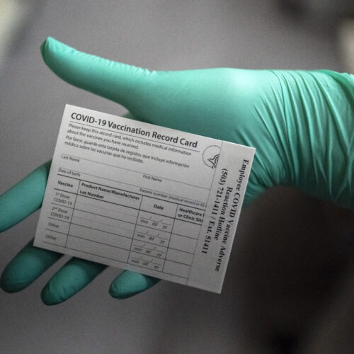 A healthcare worker displays a COVID-19 vaccine record card at the Portland Veterans Affairs Medical Center in December. CREDIT: Nathan Howard/Getty Images