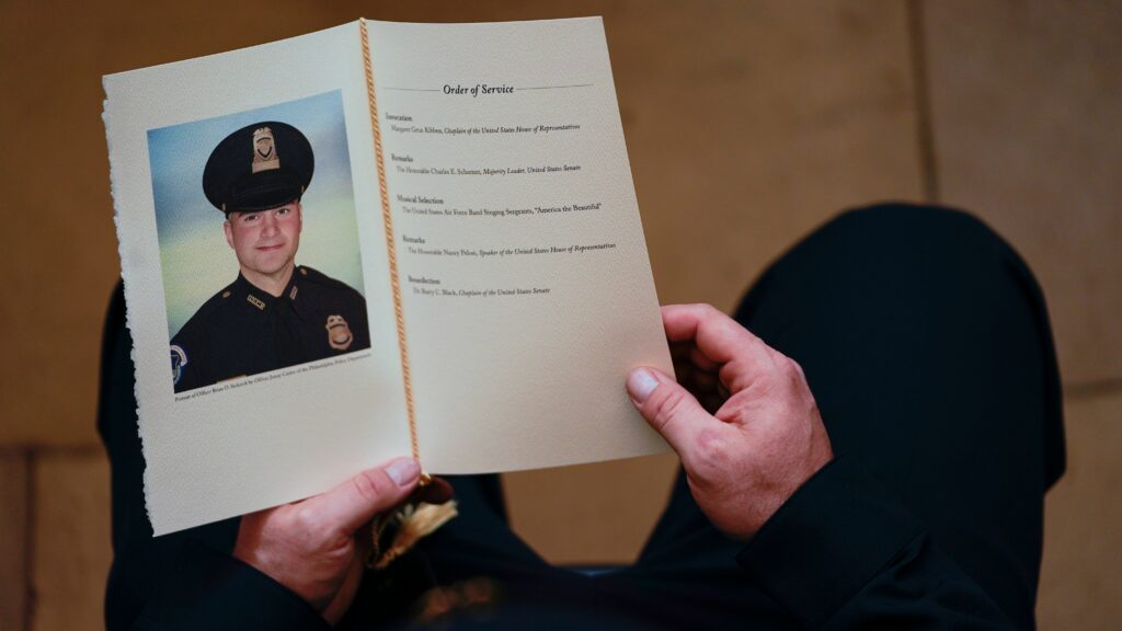 A U.S. Capitol Police officer holds a program as Brian Sicknick lays in honor in the Capitol Rotunda on Feb. 3. A medical examiner has determined that Officer Sicknick died of natural causes following the Jan. 6 insurrection. Demetrius Freeman/Pool/AFP via Getty Images