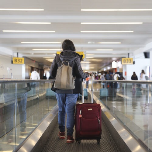 A traveler walks on a moving walkway in Terminal 4 at John F. Kennedy International Airport (JFK) in New York, U.S., on Friday, March 26, 2021. The TSA screened more than 1.3 million people both Friday and Sunday, setting a new high since the coronavirus outbreak devastated travel a year ago. Airlines say they believe the numbers are heading up, with more people booking flights for spring and summer, reports the Associated Press. Photographer: Angus Mordant/Bloomberg via Getty Images