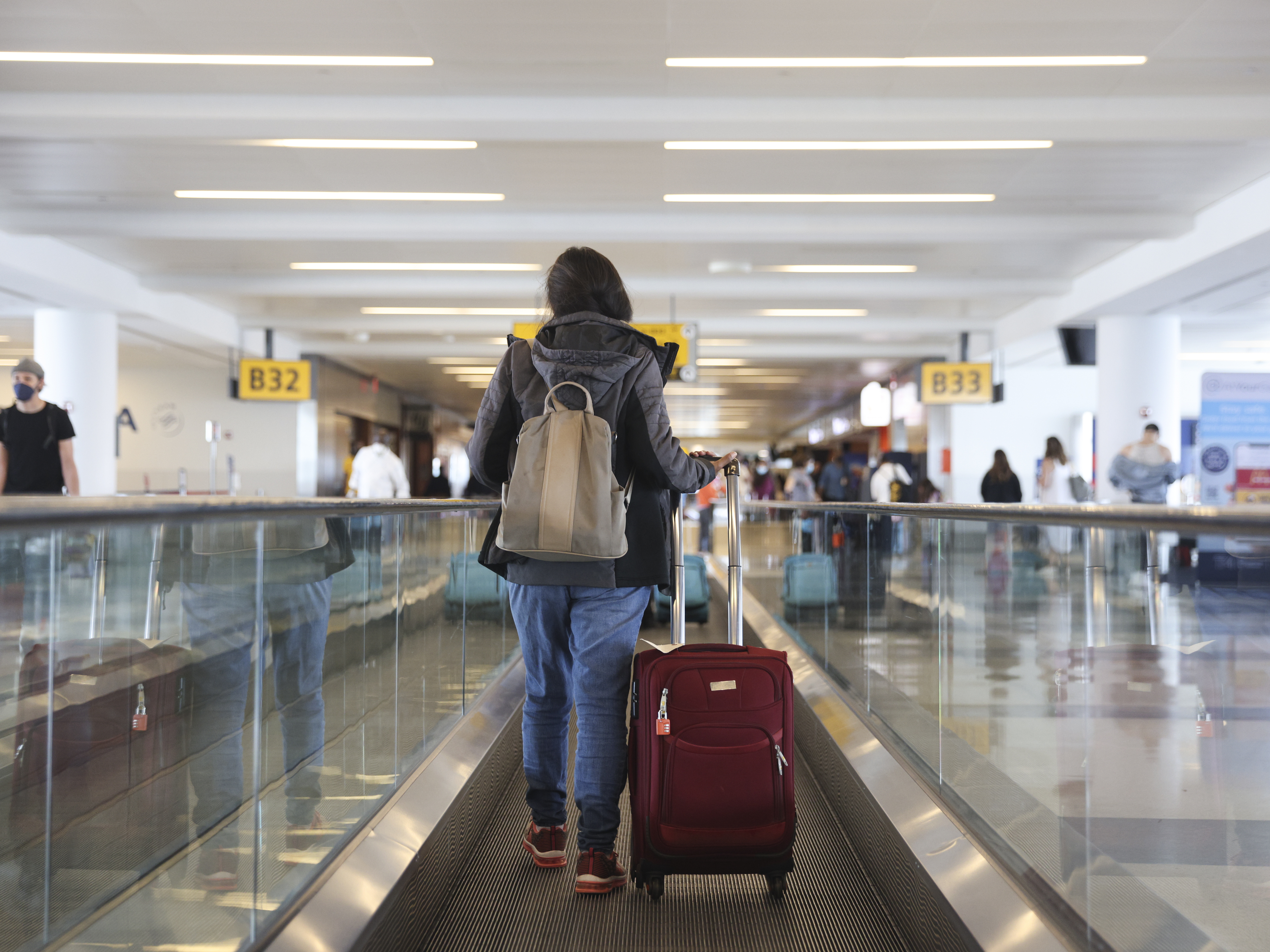 A traveler walks on a moving walkway in Terminal 4 at John F. Kennedy International Airport (JFK) in New York, U.S., on Friday, March 26, 2021. The TSA screened more than 1.3 million people both Friday and Sunday, setting a new high since the coronavirus outbreak devastated travel a year ago. Airlines say they believe the numbers are heading up, with more people booking flights for spring and summer, reports the Associated Press. Photographer: Angus Mordant/Bloomberg via Getty Images