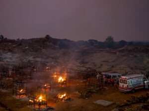 Funeral pyres burn in a disused granite quarry repurposed to cremate the dead due to COVID-19 on Friday in Bengaluru, India. The U.S. is set to impose new travel restrictions against travelers from the country. CREDIT: Abhishek Chinnappa/Getty Images