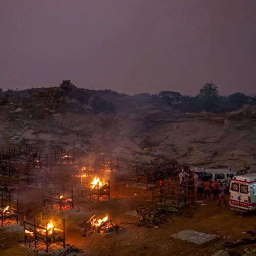 Funeral pyres burn in a disused granite quarry repurposed to cremate the dead due to COVID-19 on Friday in Bengaluru, India. The U.S. is set to impose new travel restrictions against travelers from the country. CREDIT: Abhishek Chinnappa/Getty Images