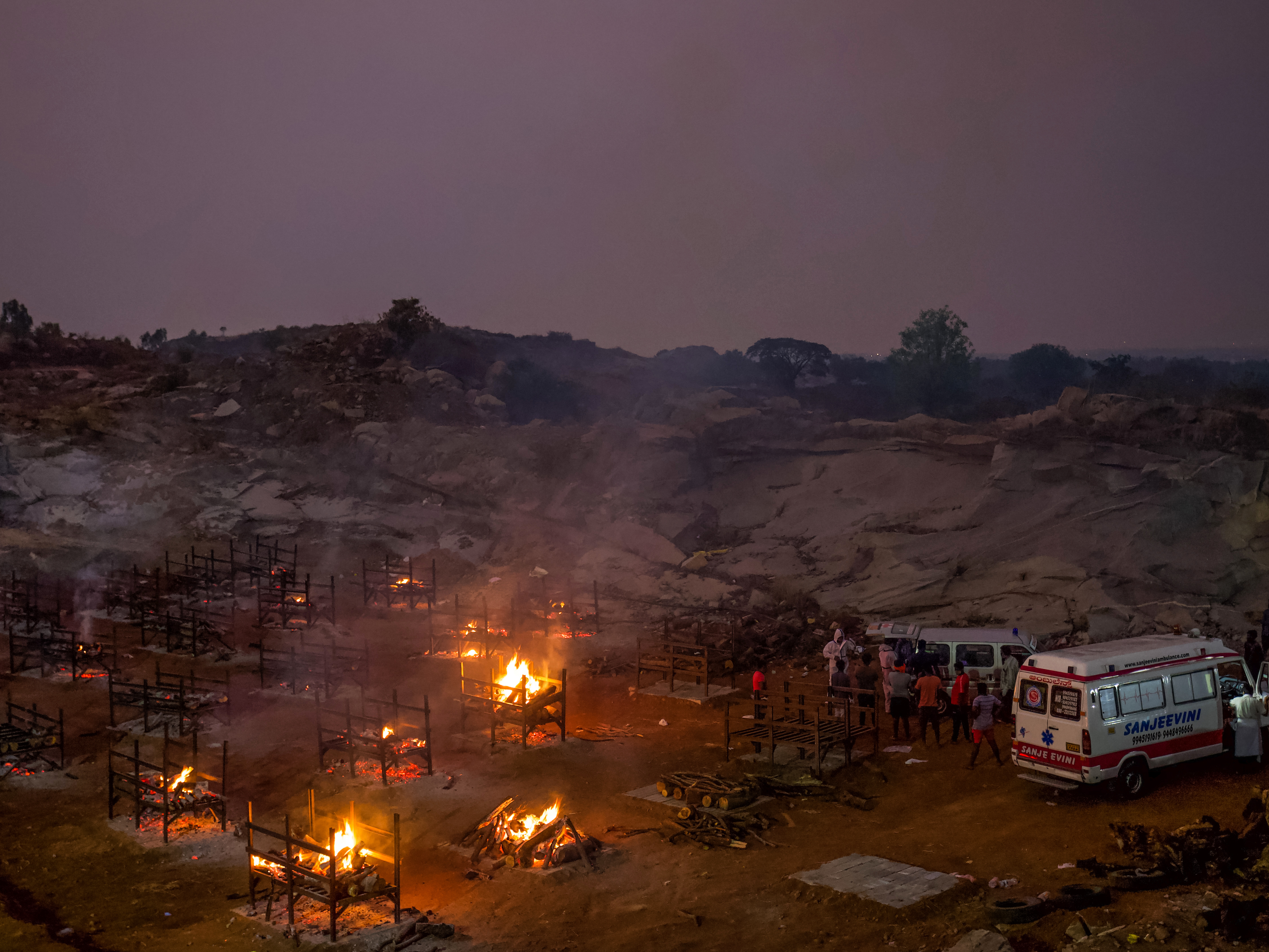 Funeral pyres burn in a disused granite quarry repurposed to cremate the dead due to COVID-19 on Friday in Bengaluru, India. The U.S. is set to impose new travel restrictions against travelers from the country. CREDIT: Abhishek Chinnappa/Getty Images