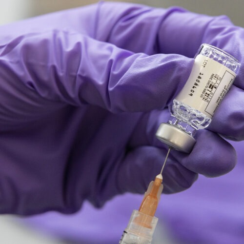 syringe going into a vial of COVID-19 vaccine