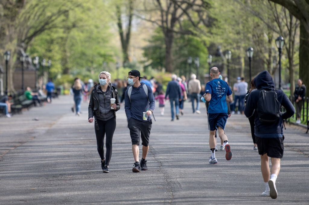 People walking in a park some wearing masks