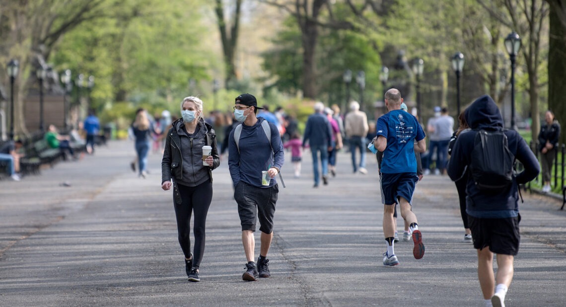 People walking in a park some wearing masks