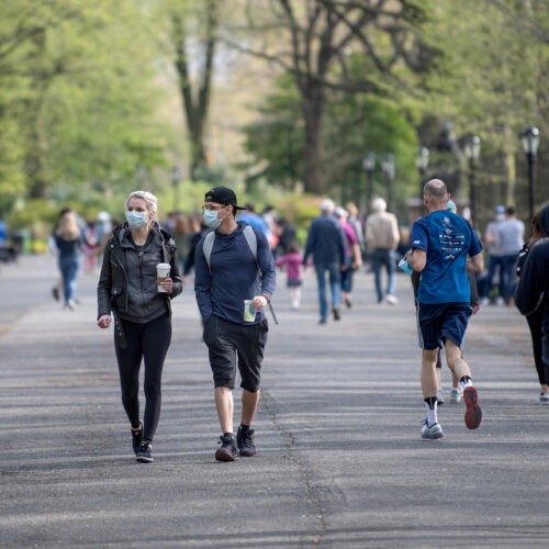 People walking in a park some wearing masks