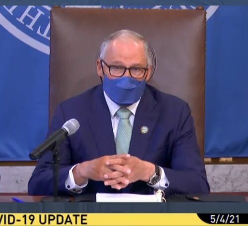 Washington Governor Jay Inslee wearing a mask and speaking from his desk during a press conference
