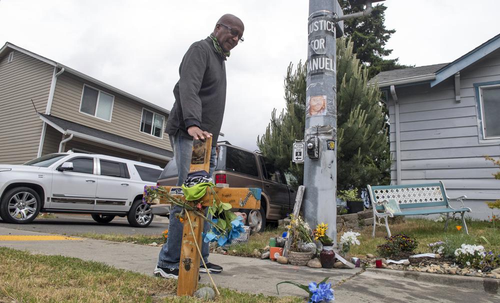 Billy Williams stops by a memorial Thursday, May 27, 2021, in Tacoma, where Manuel Ellis died while in police custody. The same day, Washington state attorney general Bob Ferguson charged two Tacoma police officers with murder and one with manslaughter in the death of Ellis, a Black man who died after telling them he couldn’t breathe as he was being restrained in March 2020. CREDIT: Tony Overman/The News Tribune via AP