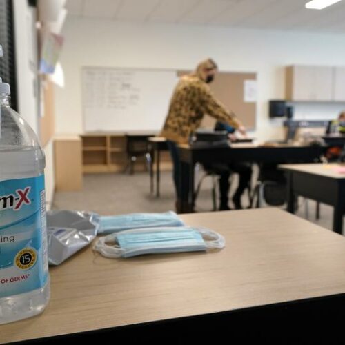 File photo. Hand sanitizer, wipes, and surgical masks rest on a desk in a fourth-grade classroom at Elk Ridge Elementary School in Buckley, Wash. State authorities said May 13, 2021, all schools in the state must provide full-time, in-person education for students for the 2021-22 school year and that students and staff will still be required to wear masks as a COVID-19 mitigation effort. CREDIT: Ted S. Warren / AP