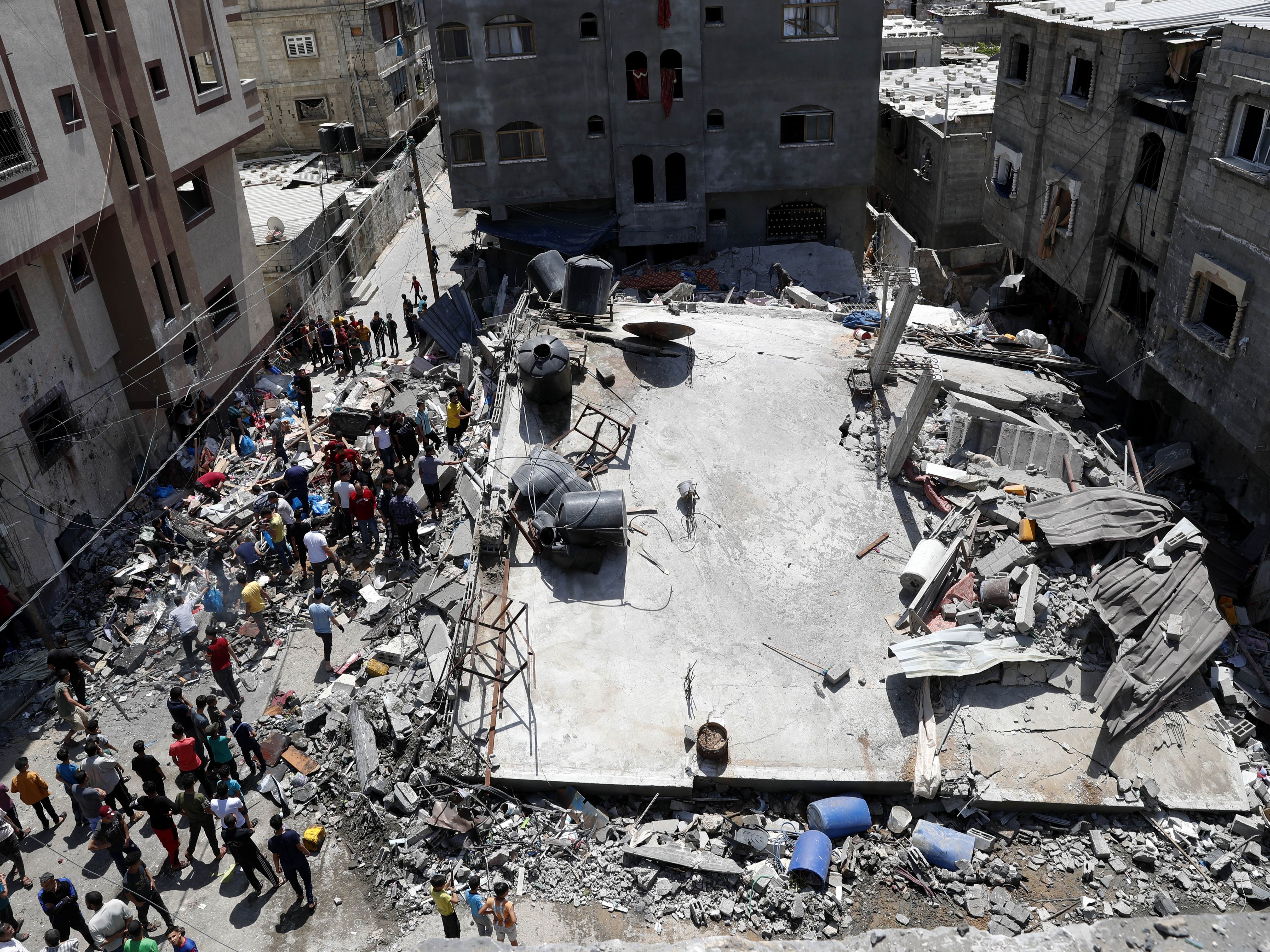 People gather near the rubble of a residential building hit by Israeli airstrikes Thursday in Beit Lahiya, Gaza Strip. CREDIT: Adel Hana/AP