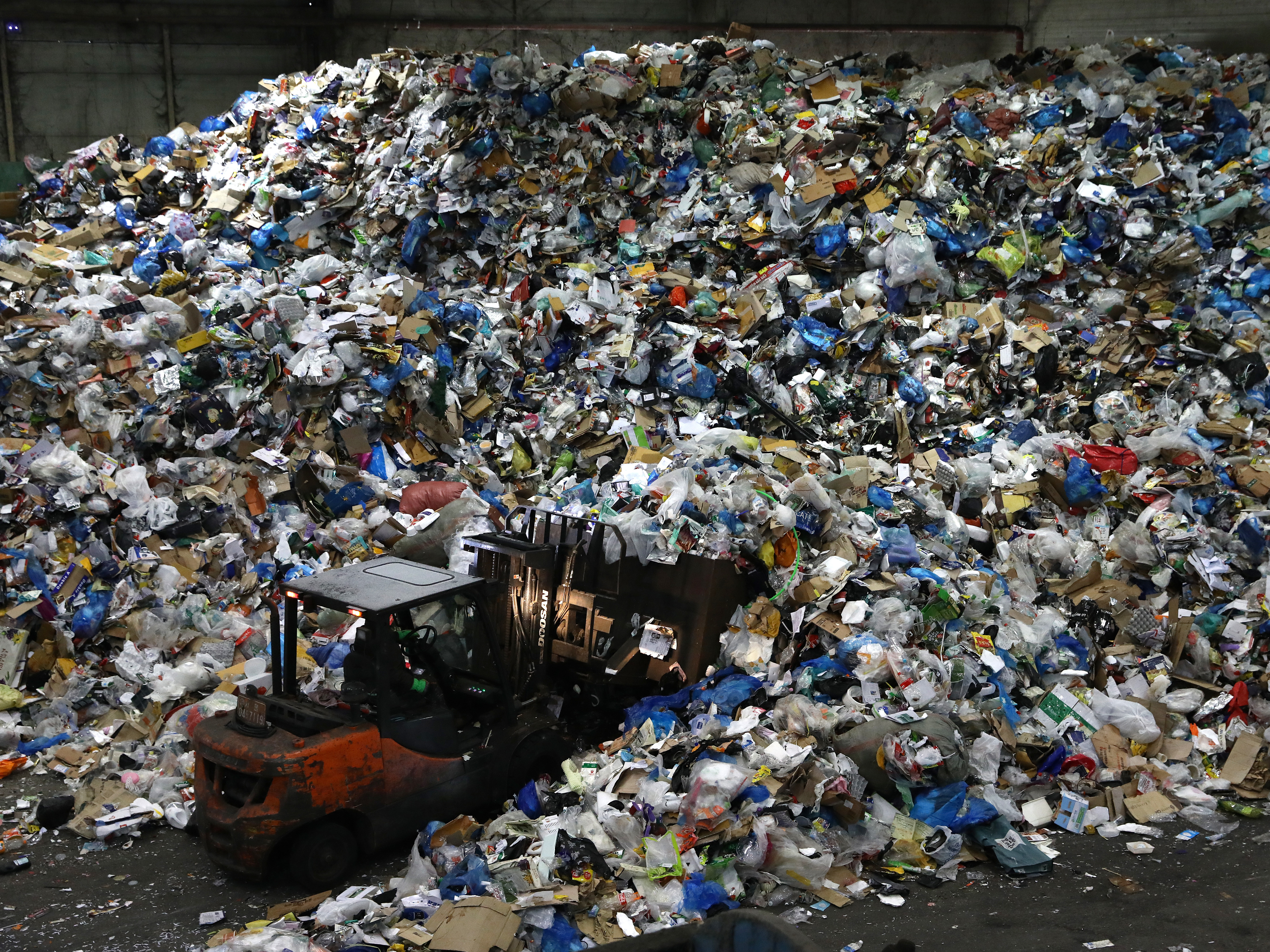 A worker operates a forklift to move household waste at a facility that stores recyclable materials in Seoul, South Korea. In 2019, more than 130 million metric tons of single-use plastics were thrown away, according to a new report. CREDIT: Chung Sung-Jun/Getty Images