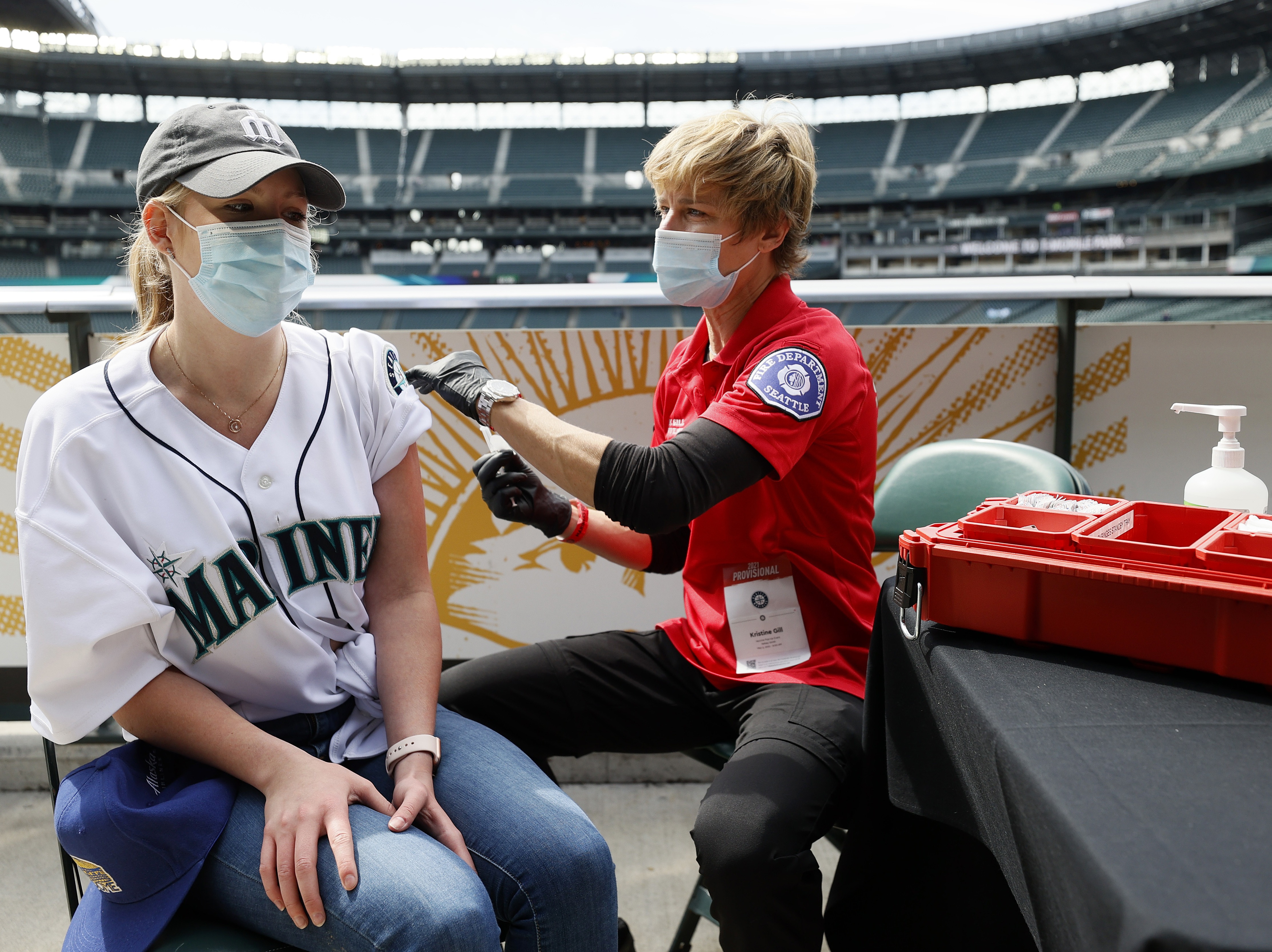 Sydney Porter of Bellevue, Wash., receives her COVID-19 vaccination from Kristine Gill, with the Seattle Fire Department's Mobile Vaccination Teams, before the game between the Seattle Mariners and the Baltimore Orioles at T-Mobile Park on May 5 in Seattle. A late spring COVID-19 surge has filled hospitals in the metro areas around Seattle. CREDIT: Steph Chambers/Getty Images