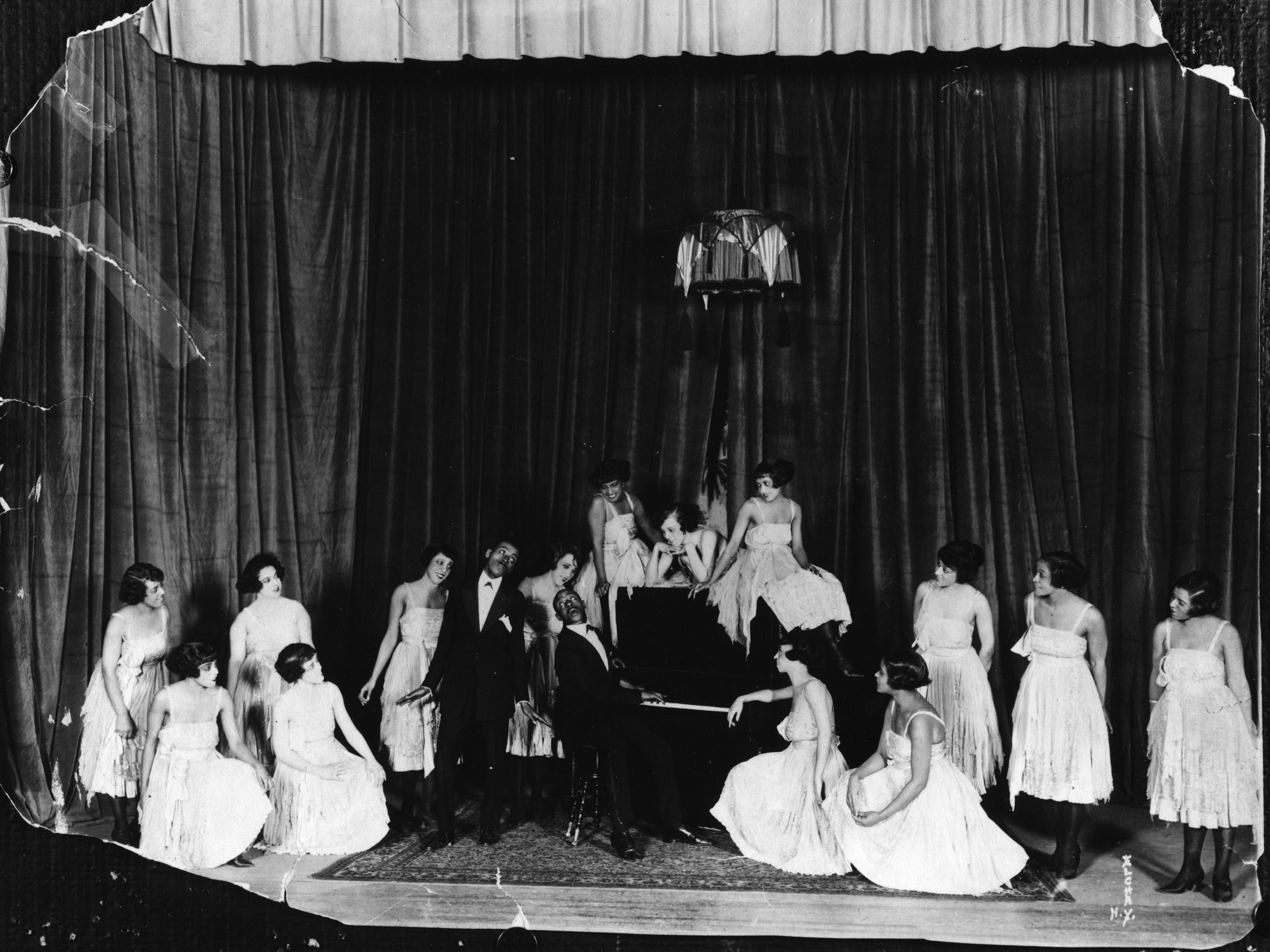 American composers and musicians Noble Sissle, center left, and Eubie Blake, on piano, perform with a group of women on stage in the early 20th century. Sissle and Blake wrote the score for Shuffle Along. Anthony Barboza/Getty Images