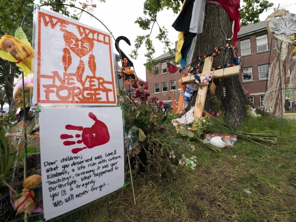 A memorial stands outside the Residential School in Kamloops, British Columbia. The remains of 215 children were discovered buried near the former Kamloops Indian Residential School earlier this month. Jonathan Hayward/The Canadian Press via AP