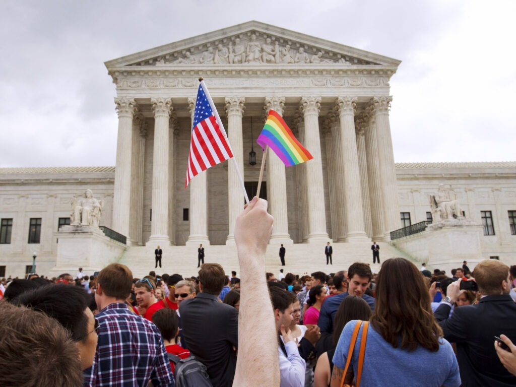A man holds a U.S. and a rainbow flag outside the Supreme Court in Washington, D.C., on June 26, 2015, after the court legalized gay marriage nationwide. CREDIT: Jacquelyn Martin/AP