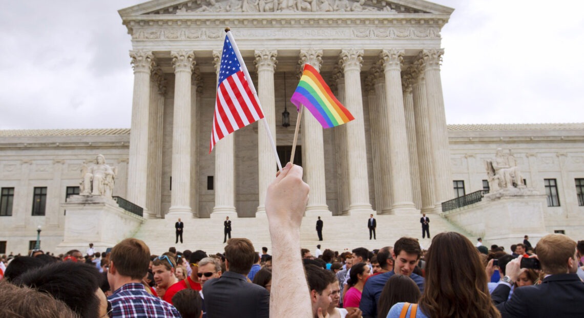 A man holds a U.S. and a rainbow flag outside the Supreme Court in Washington, D.C., on June 26, 2015, after the court legalized gay marriage nationwide. CREDIT: Jacquelyn Martin/AP