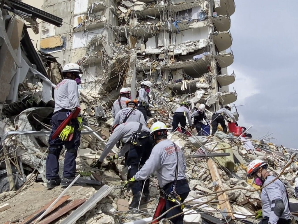 In this photo provided by Miami-Dade Fire Rescue, search-and-rescue personnel search for survivors through the rubble at the Champlain Towers South Condo in Surfside, Fla., on Friday. Via AP