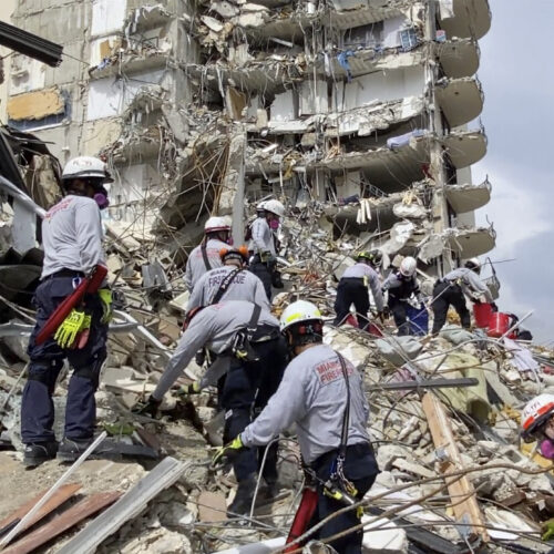 In this photo provided by Miami-Dade Fire Rescue, search-and-rescue personnel search for survivors through the rubble at the Champlain Towers South Condo in Surfside, Fla., on Friday. Via AP