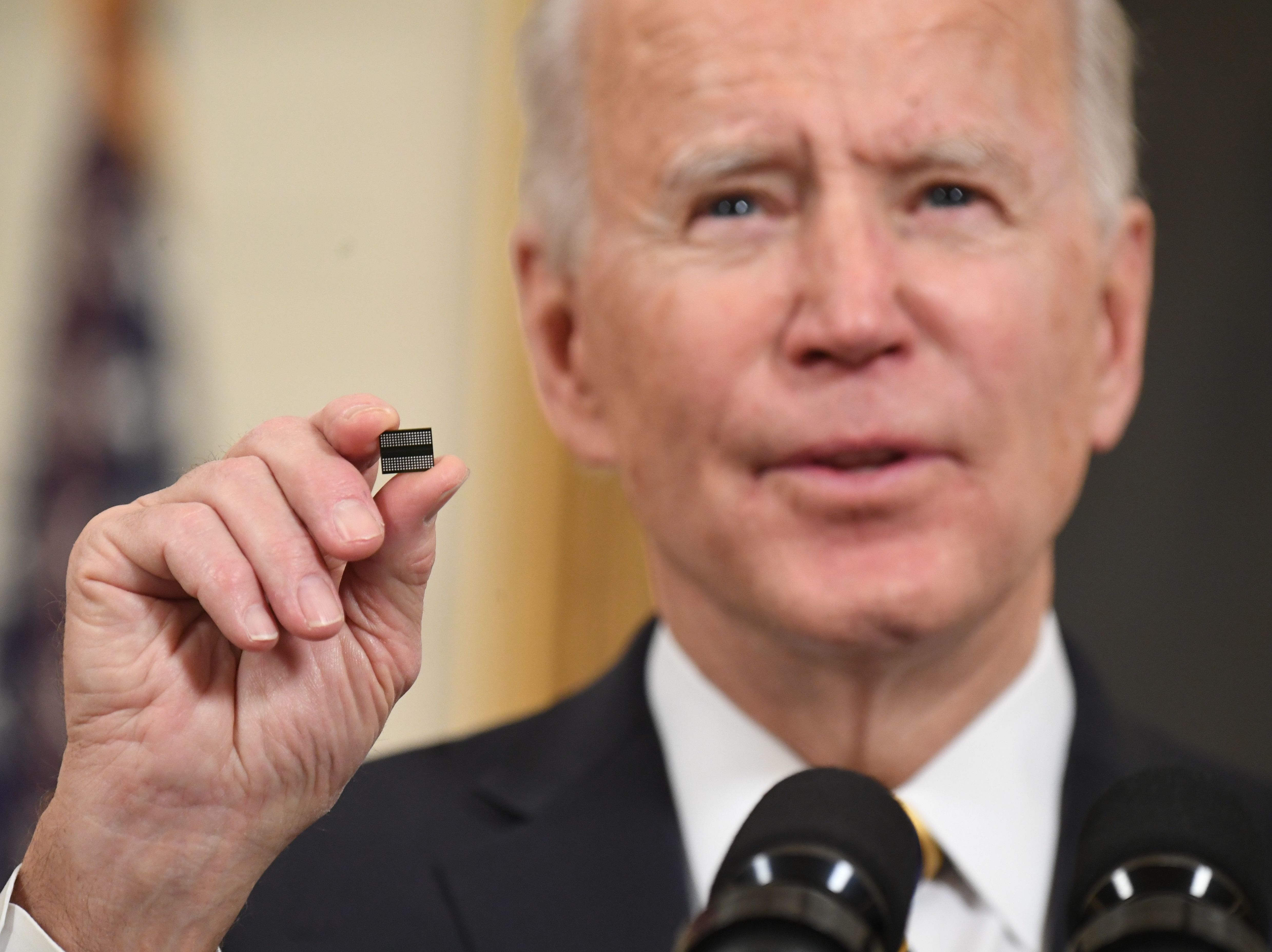 President Biden holds a microchip before signing an executive order on securing critical supply chains in February. A shortage of chips after a surge in demand hampered key sectors such as carmakers.