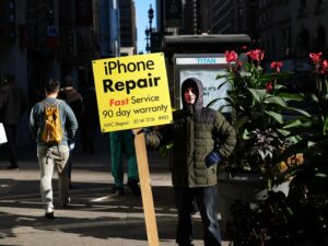 A man displays an advertisement for repairing iPhone in New York on October 19, 2015. AFP PHOTO/JEWEL SAMAD (Photo credit should read JEWEL SAMAD/AFP via Getty Images)