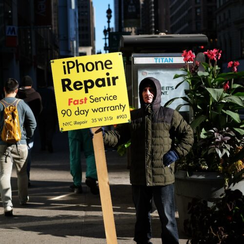 A man displays an advertisement for repairing iPhone in New York on October 19, 2015. AFP PHOTO/JEWEL SAMAD (Photo credit should read JEWEL SAMAD/AFP via Getty Images)