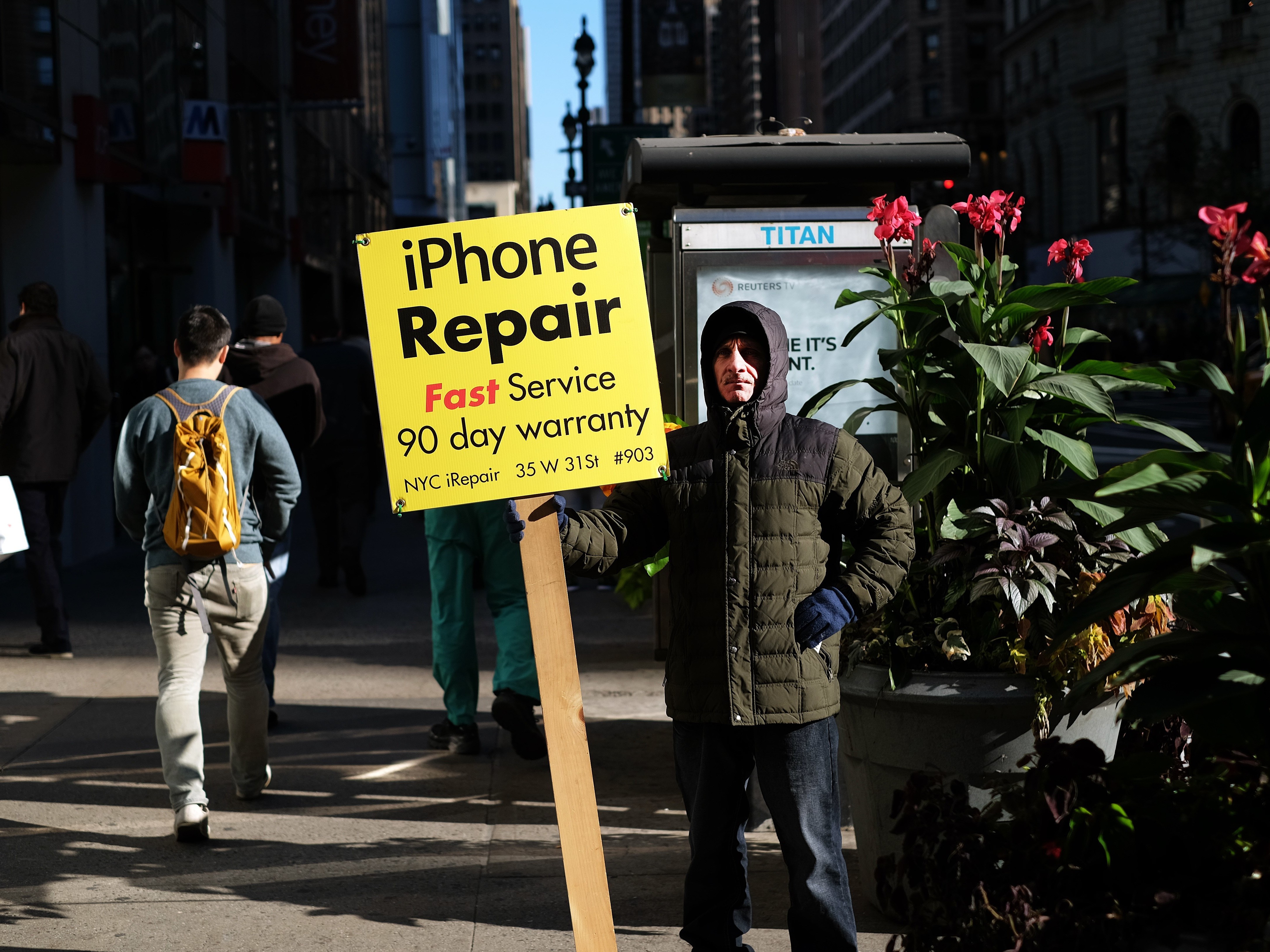 A man displays an advertisement for repairing iPhone in New York on October 19, 2015. AFP PHOTO/JEWEL SAMAD        (Photo credit should read JEWEL SAMAD/AFP via Getty Images)