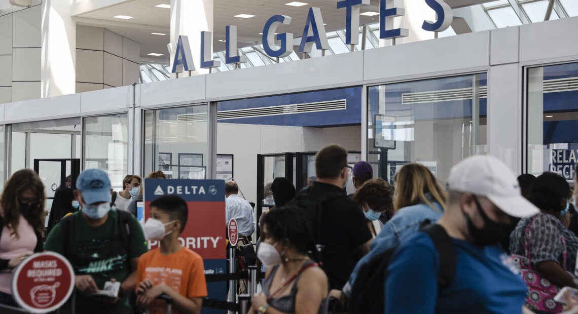 Travelers wearing protective face masks wait in line at a Transportation Security Administration screening at LaGuardia Airport in New York last month. U.S. aviation regulators are calling on the nation's airports to crack down on the defiantly unmasked.