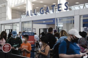 Travelers wearing protective face masks wait in line at a Transportation Security Administration screening at LaGuardia Airport in New York last month. U.S. aviation regulators are calling on the nation's airports to crack down on the defiantly unmasked.