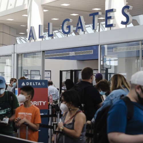 Travelers wearing protective face masks wait in line at a Transportation Security Administration screening at LaGuardia Airport in New York last month. U.S. aviation regulators are calling on the nation's airports to crack down on the defiantly unmasked.