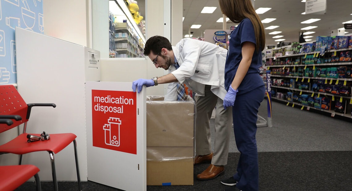 CVS Pharmacist Raphael Lynne (left), D., MBA, and Stephanie Garcia, a Pharmacy tech., check the medication disposal box where people can drop off their expired, unused or unwanted medications for safe disposal.
