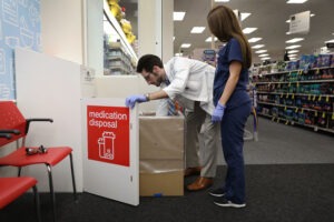 CVS Pharmacist Raphael Lynne (left), D., MBA, and Stephanie Garcia, a Pharmacy tech., check the medication disposal box where people can drop off their expired, unused or unwanted medications for safe disposal.