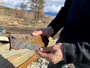 Peter Polson holds a piece of a wood stove that burned, along with a 120-year-old settler's cabin, in the Cedar Creek fire.