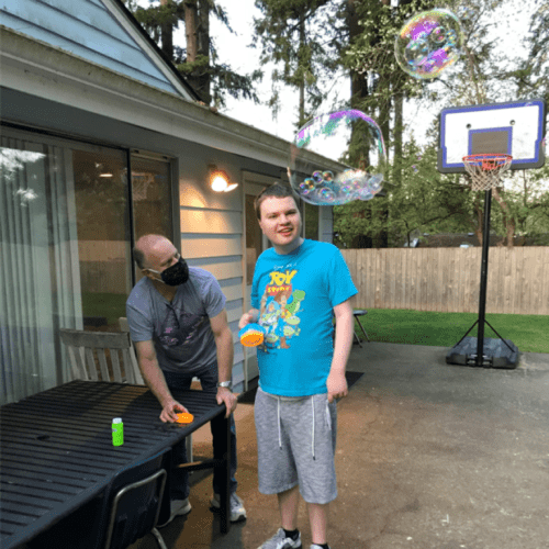 Andrew Simmons, right, blows bubbles with his father Bo last spring. Andrew, who's profoundly autistic and mostly non-verbal, lives in a supported living home in Snohomish County operated by Aacres WA, a troubled state contractor. Bo Simmons says conditions in the home over the past year have deteriorated to the point of being dangerous for Andrew and his housemates.