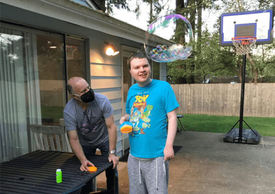 Andrew Simmons, right, blows bubbles with his father Bo last spring. Andrew, who's profoundly autistic and mostly non-verbal, lives in a supported living home in Snohomish County operated by Aacres WA, a troubled state contractor. Bo Simmons says conditions in the home over the past year have deteriorated to the point of being dangerous for Andrew and his housemates.