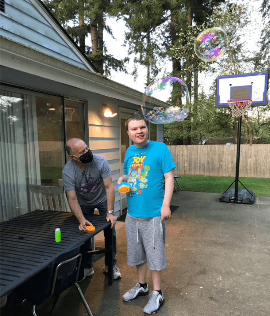 Andrew Simmons, right, blows bubbles with his father Bo last spring. Andrew, who's profoundly autistic and mostly non-verbal, lives in a supported living home in Snohomish County operated by Aacres WA, a troubled state contractor. Bo Simmons says conditions in the home over the past year have deteriorated to the point of being dangerous for Andrew and his housemates.