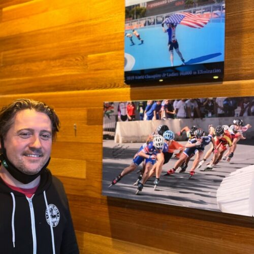 Inline skating coach Darin Pattison proudly stands beside some of the many photos of one of his proteges, Olympic short track speedskater Corinne Stoddard of Federal Way, WA, at the Pattison West roller rink in Stoddard’s hometown.