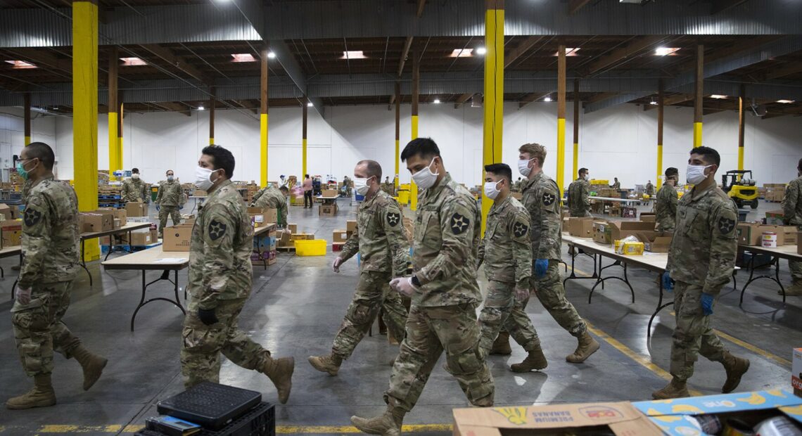 Washington National Guard soldiers walk through the Food Lifeline Covid Response Center on Tuesday, April 21, 2020, along East Marginal Way South in Seattle.