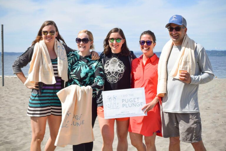 A handful of people standing on the beach who participated in the Puget Plunge after the EPA Region 10 first approved the No Discharge Zone for the sound in 2018.