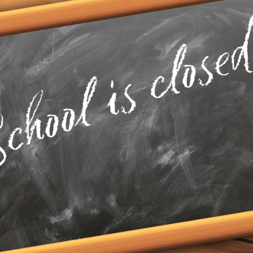A black chalk board with the writing, school closed on it.