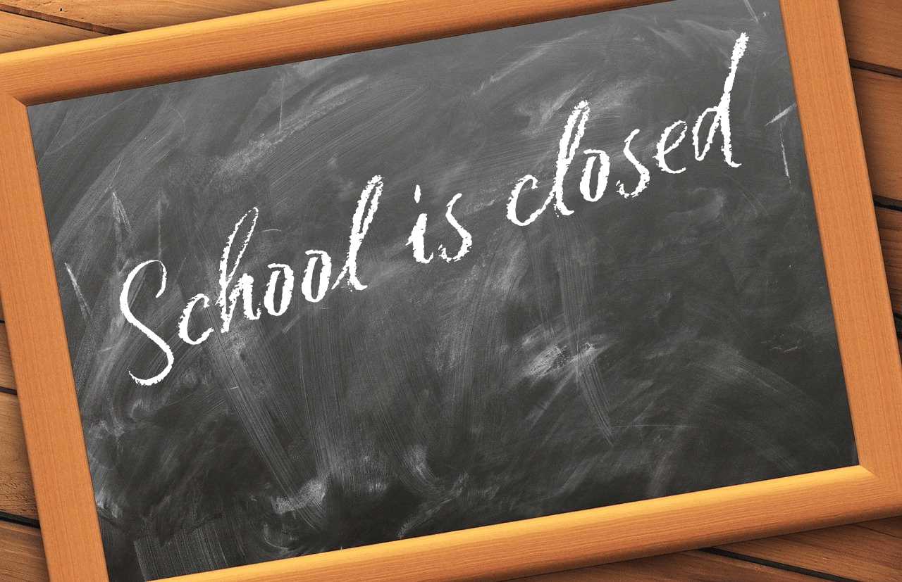 A black chalk board with the writing, school closed on it.