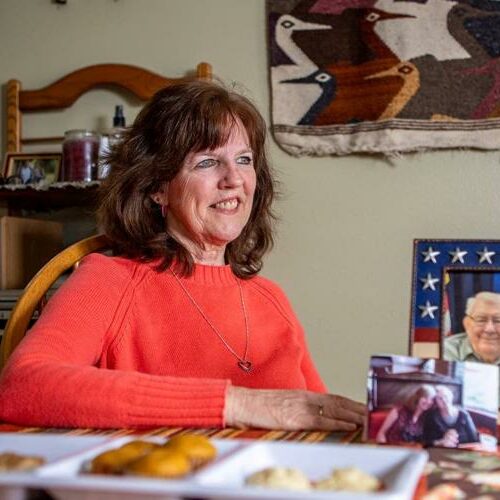 Nan Orton sitts at her kitchen table with pictures of her parents