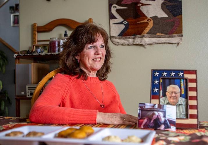 Nan Orton sitts at her kitchen table with pictures of her parents