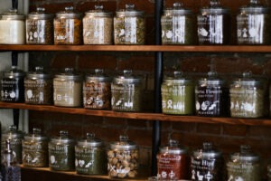 A variety of herbs and spices sit on shelves behind the front counter, featuring their names as well as what they can be used for holistically