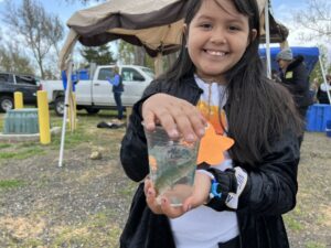 Jade Ramirez-Medrano, 9, a fourth grade student at Cascade Elementary School in Kennewick, shows off a chinook salmon shortly before she releases it into the Columbia River.